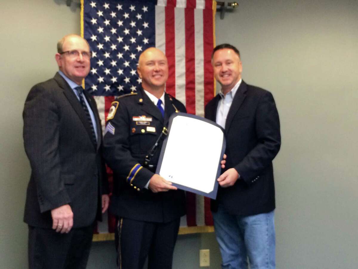 State Senators Kevin Kelly left and Rob Jane right present Seymour Police Sgt. Stephen Prajer with a certificate commending him for receiving a leadership award from Northwestern University
