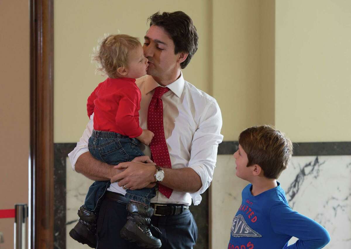 Liberal leader Justin Trudeau kisses his son, Hadrien, as son Xavier looks on while they wait to vote at a polling station Monday, Oct. 19, 2015 in Montreal. Canadians voted Monday to decide whether to extend Conservative Prime Minister Stephen Harper's near-decade in power or return Canada to its more liberal roots. (Adrian Wyld/The Canadian Press via AP) MANDATORY CREDIT