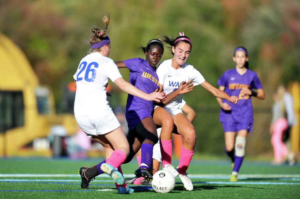 Westhill's Chelsea Domond, center, attemps to sneak past Darien defenders Megan Shanahan, left, and Charlotte Harmon during a Thursday afternoon varsity girls soccer game at Darien High School on Oct. 15, 2015.