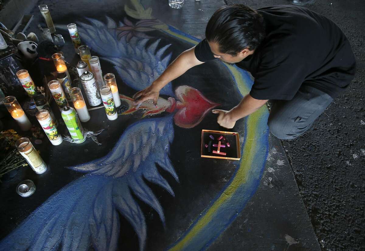 Daniel Panko sketches a design in chalk before a dedication ceremony for the Superheroes Mural Project on West Street in Oakland, Calif. on Wednesday, Oct. 21, 2015. Artist Antonio Ramos was shot and killed while working on the mural on Sept. 29.