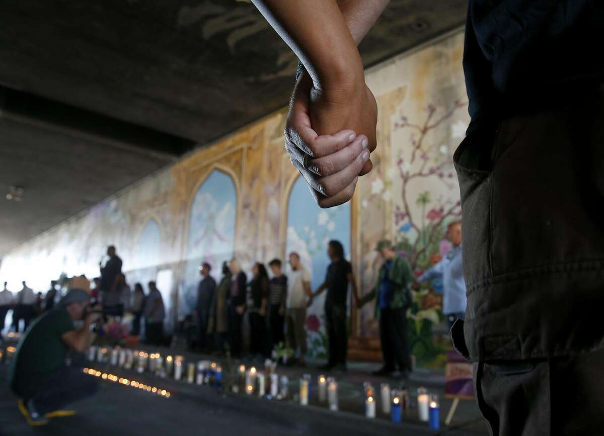 Mourners join hands during a blessing of the Superheroes Mural Project at a dedication ceremony on West Street in Oakland, Calif. on Wednesday, Oct. 21, 2015. Artist Antonio Ramos was shot and killed while working on the mural on Sept. 29.
