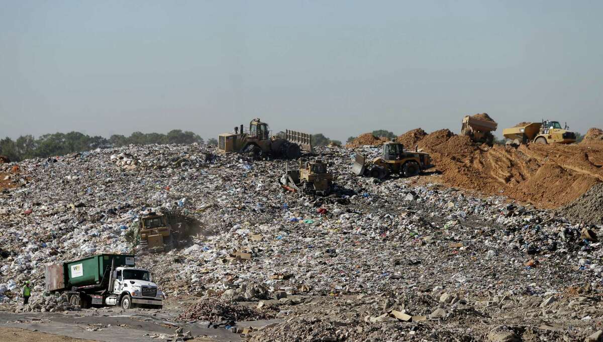 Machines work to compact trash at a landfill as trucks bring dirt that will be used to cover it at the Waste Management Atascocita recycling and disposal facility.﻿