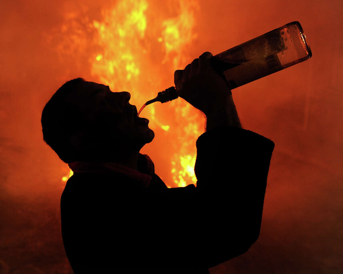 A man drinks liquor from a bottle besides a bonfire on January 16, 2012 in the small village of San Bartolome de Pinares, Spain.