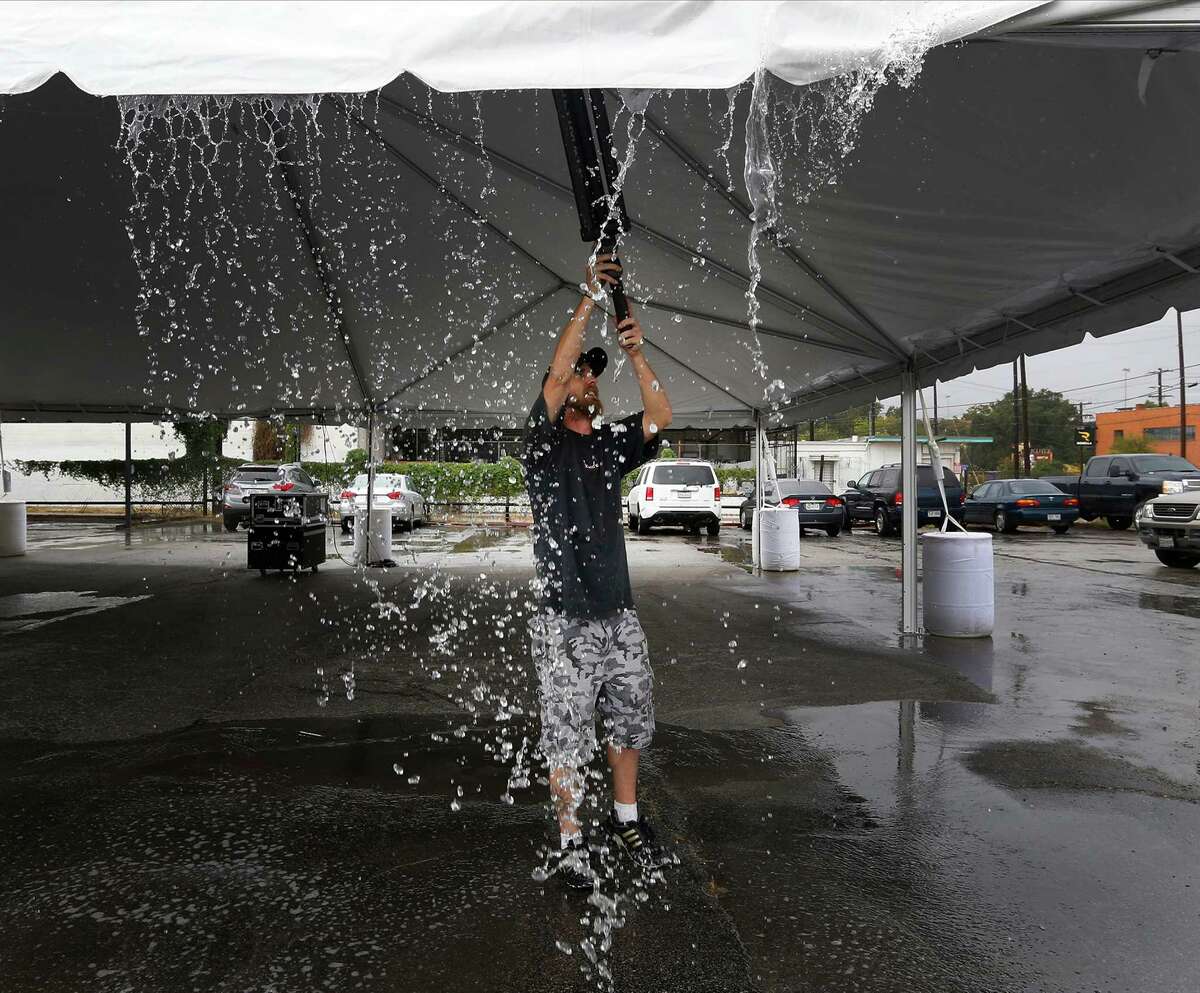 Josh Stoker clears off collected rain water on a tent where he was helping set up stage lighting and sound in preparation for the upcoming Luminaria arts festival along the stretch of the River North neighborhood on Thursday, Oct. 22, 2015. Luminaria, which started in 2008, features a variety of artwork from local, national and international artists. The event will be taking place this weekend - rain or shine.