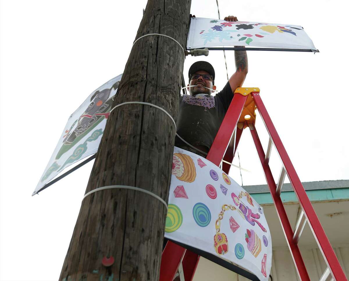 Art installer Pedro Luera hangs up reproductions of artwork from local artists as part of the City of San Antonio Department of Culture and Creative Development's public art project called RESYMBOL along Jones Avenue on Thursday, Oct. 22, 2015. The public artwork is shown in conjunction with the upcoming Luminaria arts festival along the stretch of the River North neighborhood which will be taking place this weekend - rain or shine. The reproductions being hung up by Luera are from artists: Robert Tatum (from clockwise left), Waddy Armstrong and Elizabeth Carrington.