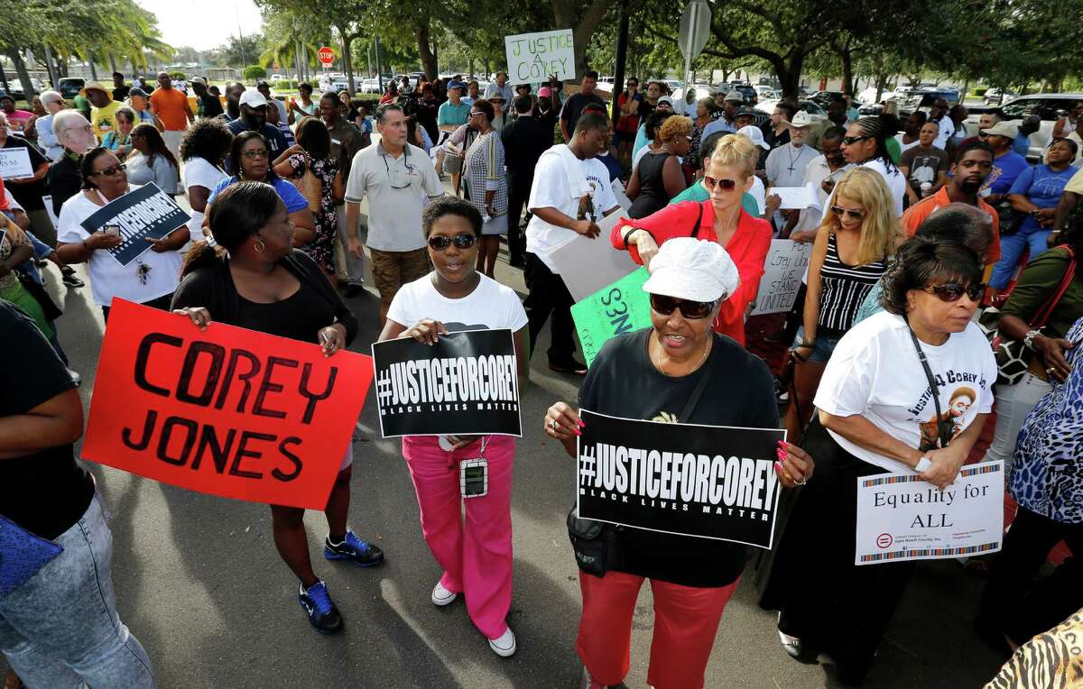Attendees hold signs in support of Corey Jones at a 'rally for answers' on Thursday, Oct. 22, 2015, in Palm Beach Gardens, Fla. Jones was fatally shot by a South Florida police officer (AP Photo/Joe Skipper)