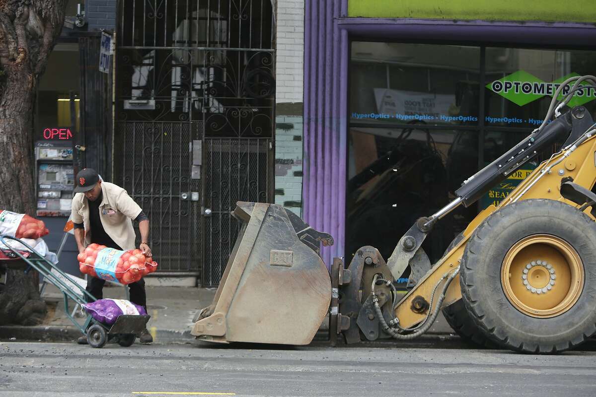 Sam Afuhaamango of Manu Produce picks up a bag of produce that had tipped over as he loads a dolly with produce next to construction equipment not being used during a delivery on Haight Street between Masonic and Ashbury on Friday, October 23, 2015 in San Francisco, Calif.