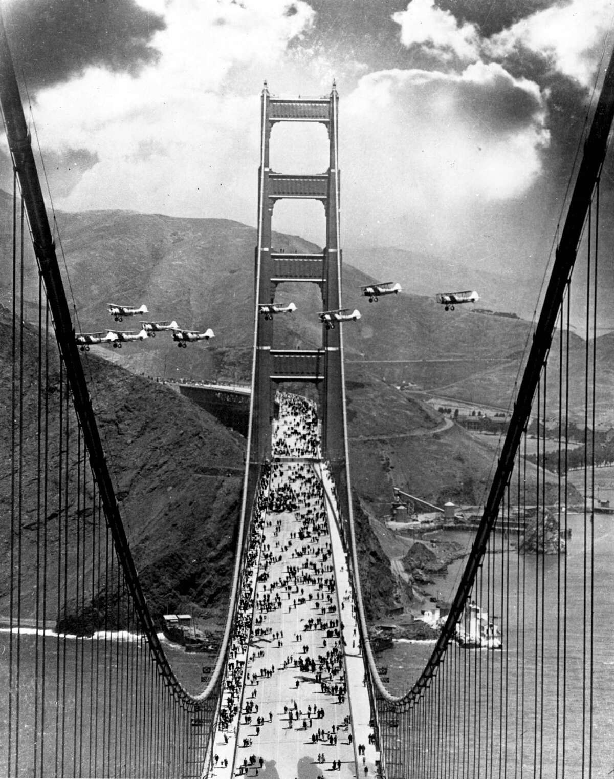 金门大桥开幕日，1937年。行人在桥上行走，飞机在南北塔之间飞行。