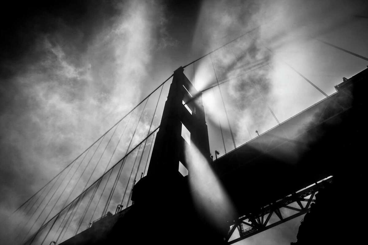 Afternoon light streams through fog blowing by the north tower of the Golden Gate Bridge in May 2012.