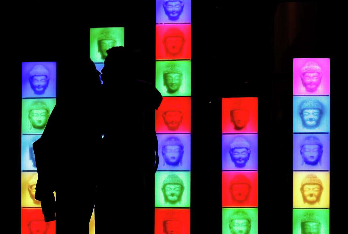Jimmie Sutton and Marlene Wetherington kiss in front of an art display at the San Antonio Museum of Art on the first night of Luminaria in the River North neighborhood. Some outdoor events had to be canceled because of the rain.