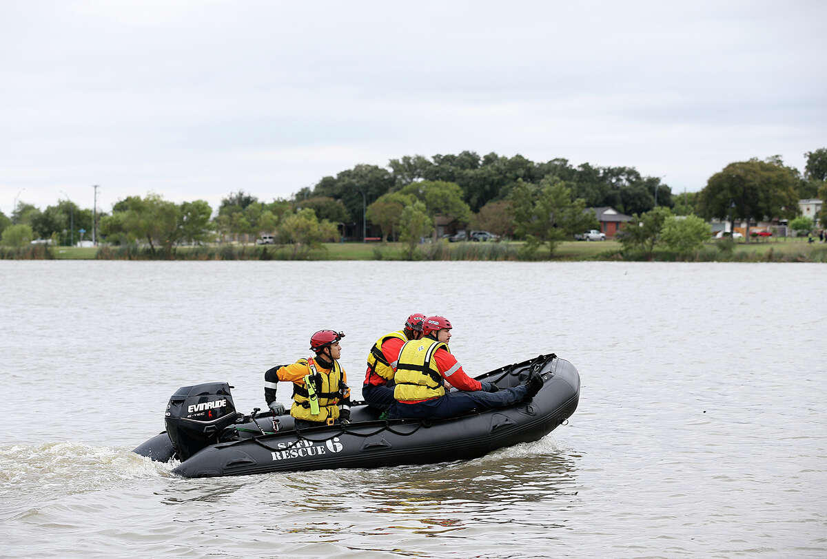 San Antonio Fire Department personnel search for a missing man at Woodlawn Lake, Sunday, Oct. 25, 2015. The man was swept away by storm waters in a drainage ditch as he went chased after his dog early Saturday morning.