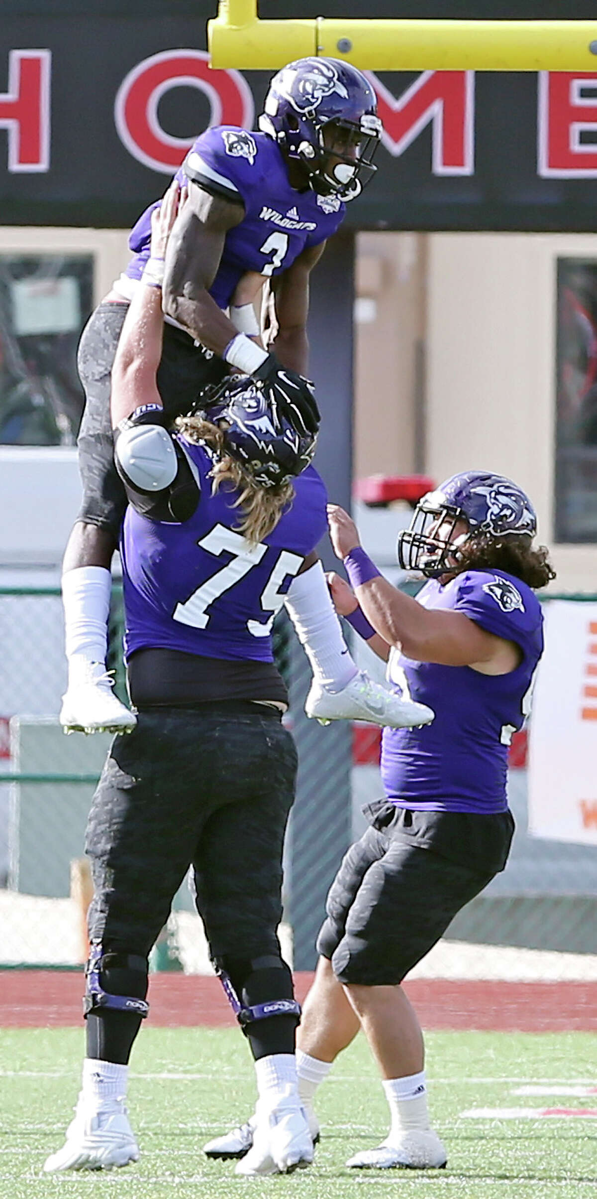 Abilene Christian University's Carl Whitley (top) celebrates with teammates Chance Rieken (left) and Frank Kee after scoring a touchdown during second half action against the University of the Incarnate Word Sunday Oct. 25, 2015 at Benson Stadium on the UIW campus. UIW won 25-20.