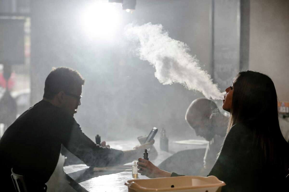 FILE - New Element Fine Vapors employee Melissa Torres, right, vapes with Nate Pingor, left, and owner Daniel Adell in the shop Oct. 26, 2015, in Houston, Texas.