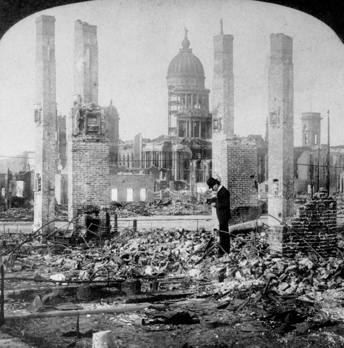 1906年:地震后，一名男子在市政厅遗迹前拍摄建筑块的废墟。