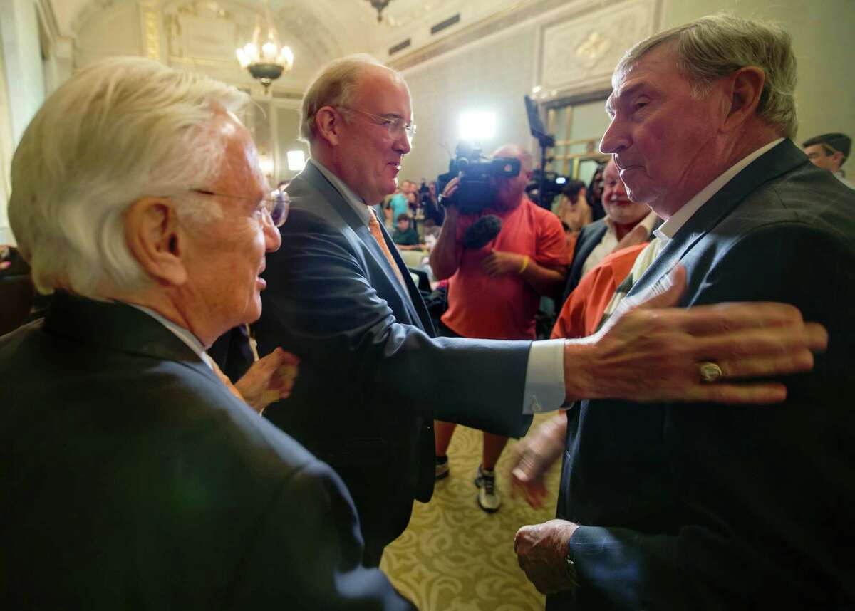 Interim Texas athletic director Mike Perrin (center) greets former AD DeLoss Dodds after a news conference on Sept. 16, 2015, in Austin.