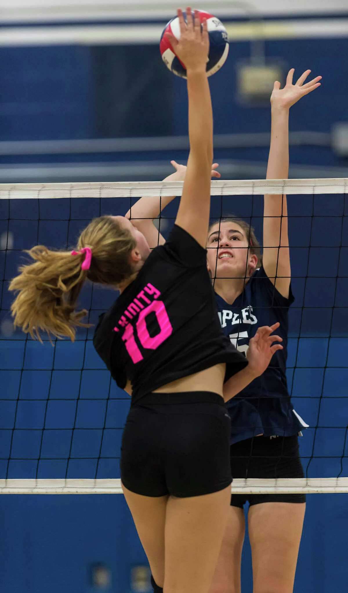 Staples High Schools Virginia Gerig goes up to try and block a spike by Trinity Catholic High Schools Emily Ellis during a girls volleyball game played at Staples High School, Westport, CT on Wednesday, October 28, 2015.