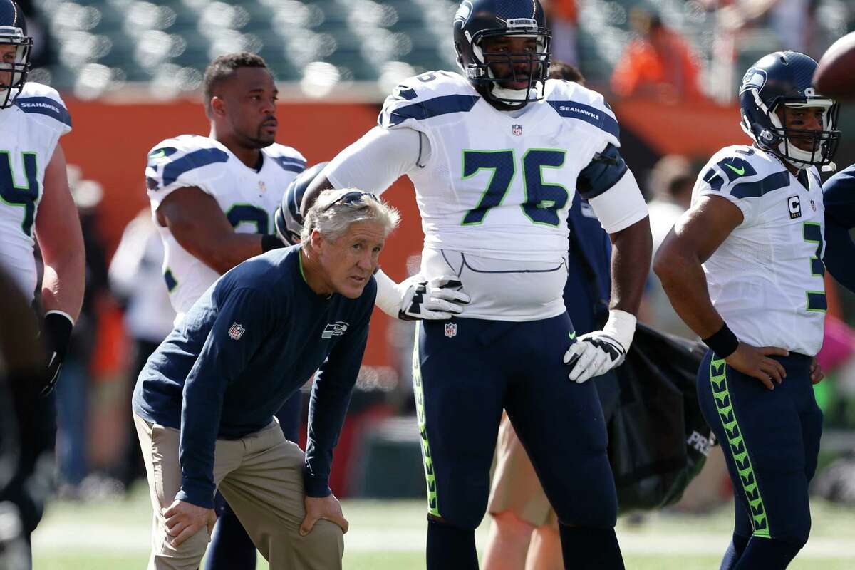 Seattle Seahawks head coach Pete Carroll, center left, works the field alongside tackle Russell Okung during practice before an NFL football game against the Cincinnati Bengals, Sunday, Oct. 11, 2015, in Cincinnati.