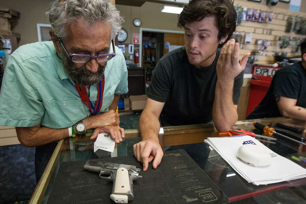 Sales associate Chris Harris, right, talks to Elliott Isenberg about his Colt .45 handgun at High Bridge Arms, Friday, Oct. 30, 2015, in San Francisco, Calif. Isenberg bought the last gun sold at the store.
