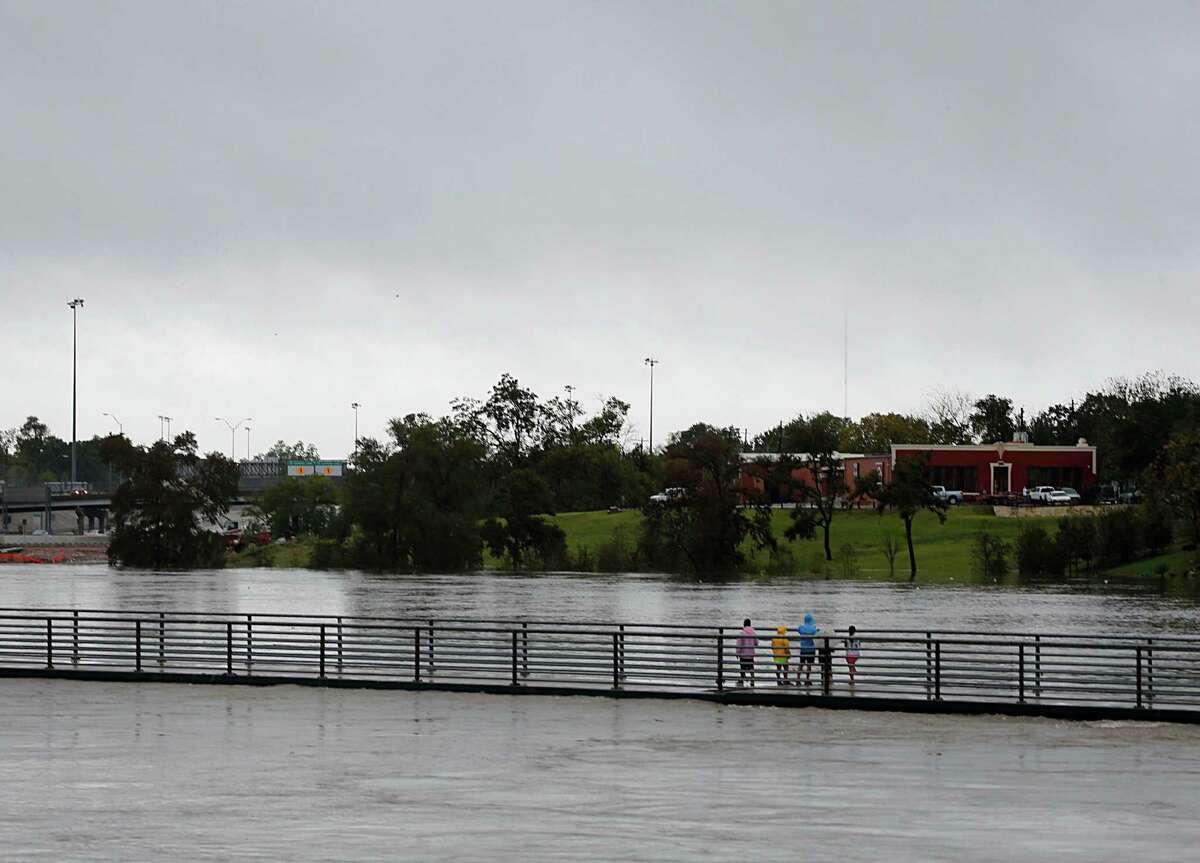People stand on a pedestrian bridge over White Oak Bayou as heavy rains fall in the area Saturday, Oct. 31, 2015, in Houston.