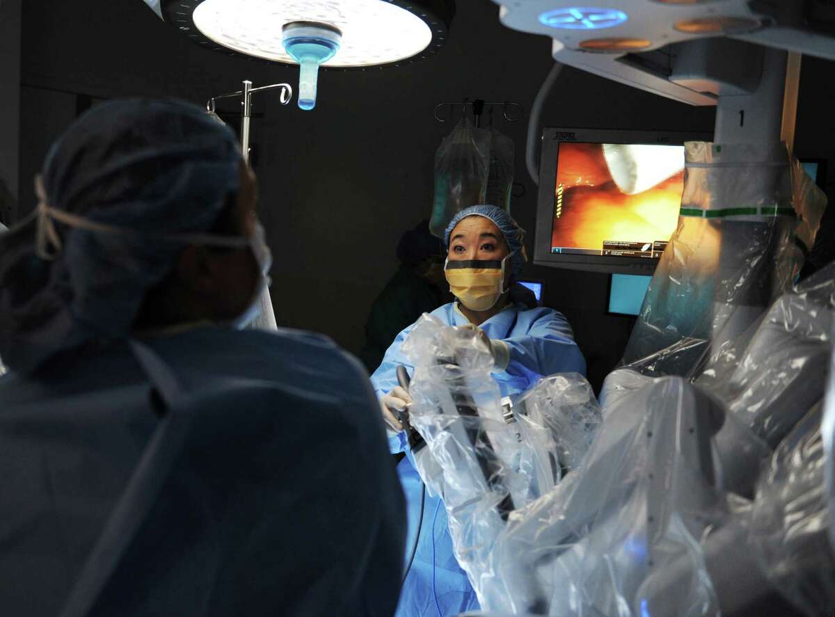 Gynecologic Oncologist Karen Nishida, M.D., sets up the arms on the da Vinci robotic surgery machine before performing a hysterectomy using the machine at Greenwich Hospital in Greenwich, Conn. Thursday, Oct. 29, 2015. The da Vinci surgical system features a 3D vision system and hand instruments that follow the movement of the surgeon's hands. The robotic system is minimally invasive, requiring fewer incisions, and enables enhanced vision, precision and control during operations.