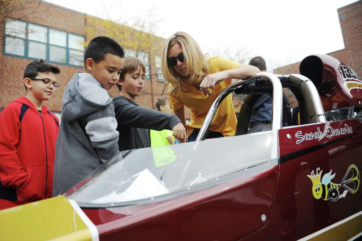NHRA drag racer Sarah Edwards shows the controls of her top dragster vehicle to fourth-graders Youssef Taoyfik, left, Allan Medina, center, and Steven Lopez at Julia A. Stark Elementary School. Edwards, a Stark School alumna and Stamford native, talked about her racing career and the science and aerodynamics of racing to a group of fourth-grade science students before letting the students get a close up look at her 1100 horsepower vehicle.
