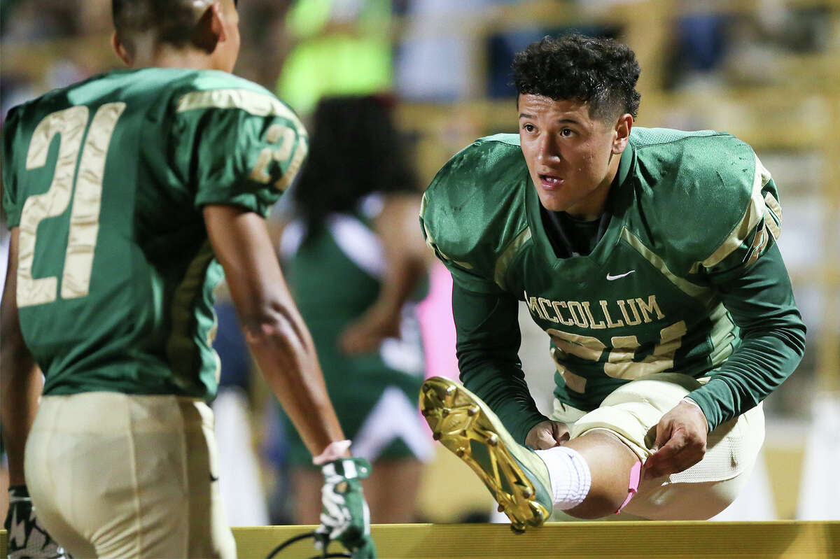McCollum running back Mike Ramirez (right) stretches on the sideline while talking to teammate Joseph Casares during the first half of their game with Brackenridge at Harlandale Memorial Stadium on Oct. 16, 2015. Ramirez scored four touchdowns on the night, three rushing and one receiving, to help the Cowboys beat Brackenridge 49-38.