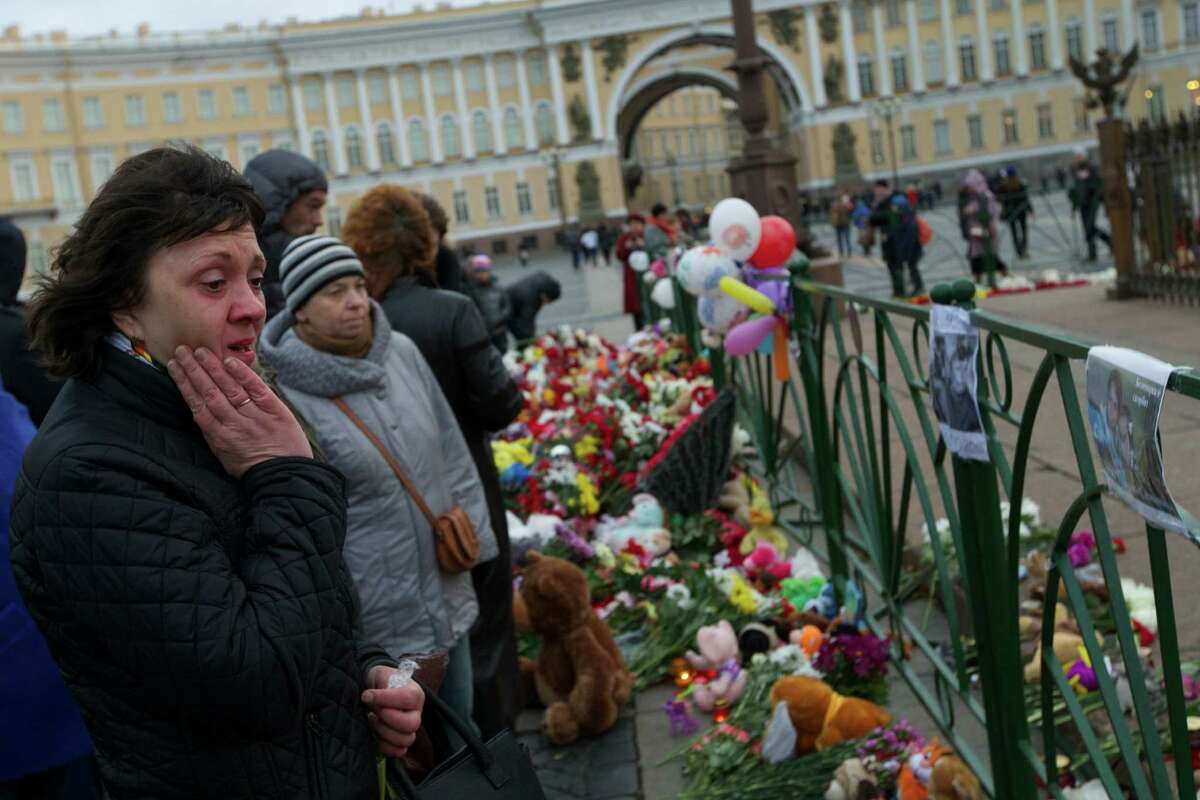 People look at photos of the plane crash victims attahced to the fence at Dvortsovaya (Palace) Square in St. Petersburg, Russia, on Monday, Nov. 2, 2015. In a massive outpouring of grief, thousands of people flocked to St. Petersburg's airport, laying flowers, soft toys and paper planes next to the pictures of the victims of the crash of a passenger jet in Egypt that killed all 224 on board in Russia's deadliest air crash to date. (AP Photo/Ivan Sekretarev) ORG XMIT: XAZ131