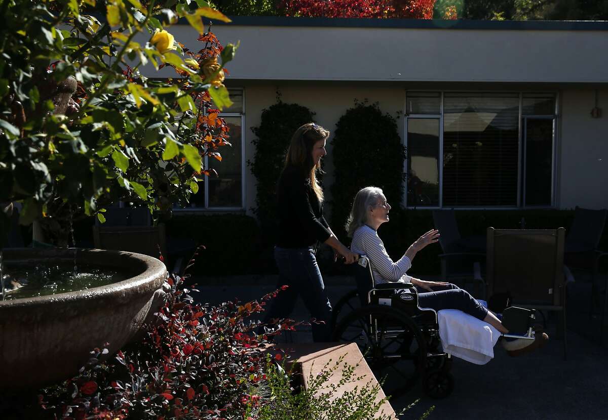 Erin Kane, 50, left, takes her mother Helen Kane, 78, who has Alzheimer's outside to sit in the sunshine after Erin did her hair at The Rafael assisted living home Nov. 3, 2015 in San Rafael, Calif. Erin took care of her mother Helen for seven years before she had to move her into an assisted living home earlier this year after it became too difficult for Erin to care for Helen on her own. Erin lives only a few miles from the home and is able to visit her mother multiple times a day.