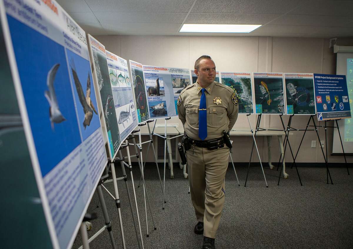 Captain Christopher Sherry, California Highway Patrol Commander of San Francisco Area, walks by environmental information posters at a media briefing regarding the pier E3 implosion planned for November 14 on Tuesday, Nov. 3, 2015 in Oakland, Calif.