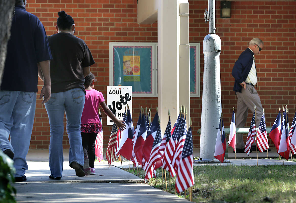 Voters are surrounded by a flag display on their way to vote on Tuesday, November 3, 2015, at Oak Grove Elementary School on Nacogdoches Rd.