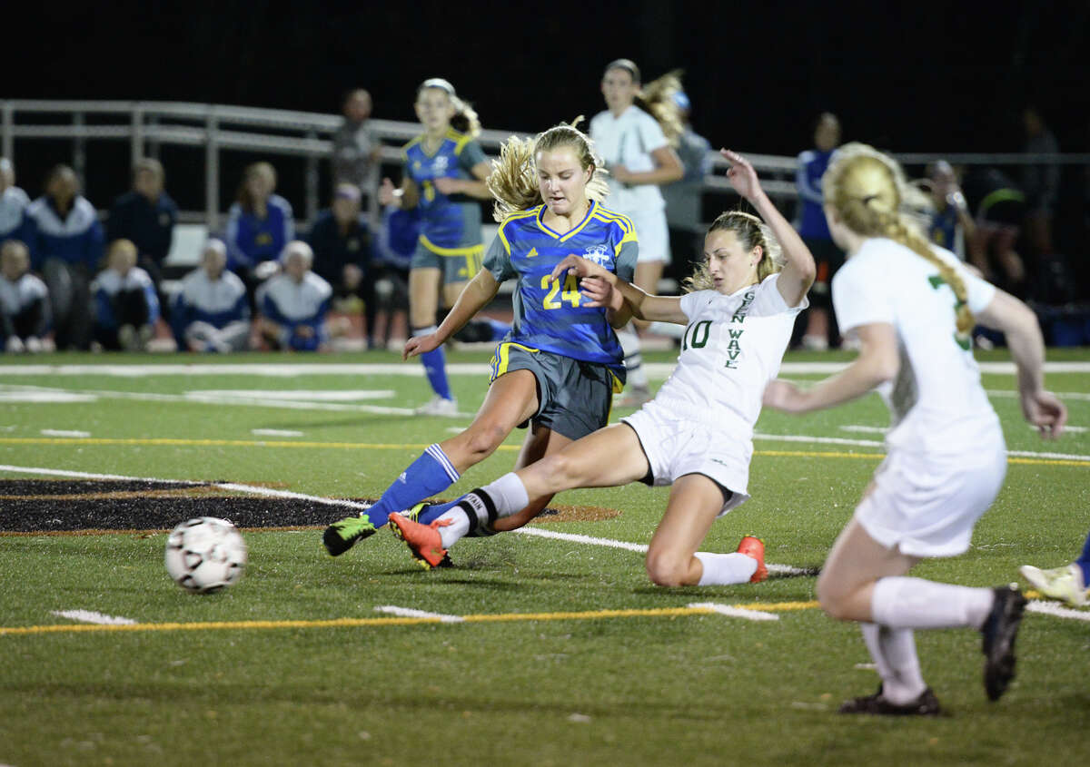 New Milford's Monica Baxter (10) tackles the ball away from Newtown's Olivia Caplan (24) during the SWC girls soccer semifinals at Barlow High School in Redding, Conn. on Tuesday, Nov. 3, 2015.