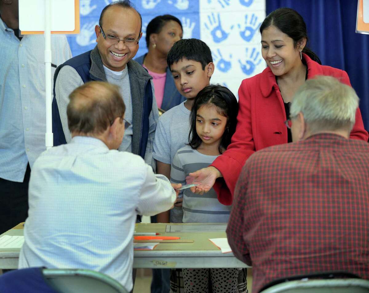 Gazi and Lema Ahmed, with their kids, Rohan,11, and Ritika, 8, check in to vote at the Stadley Rough School polling place in Danbury, Tuesday, Nov. 3, 2015.
