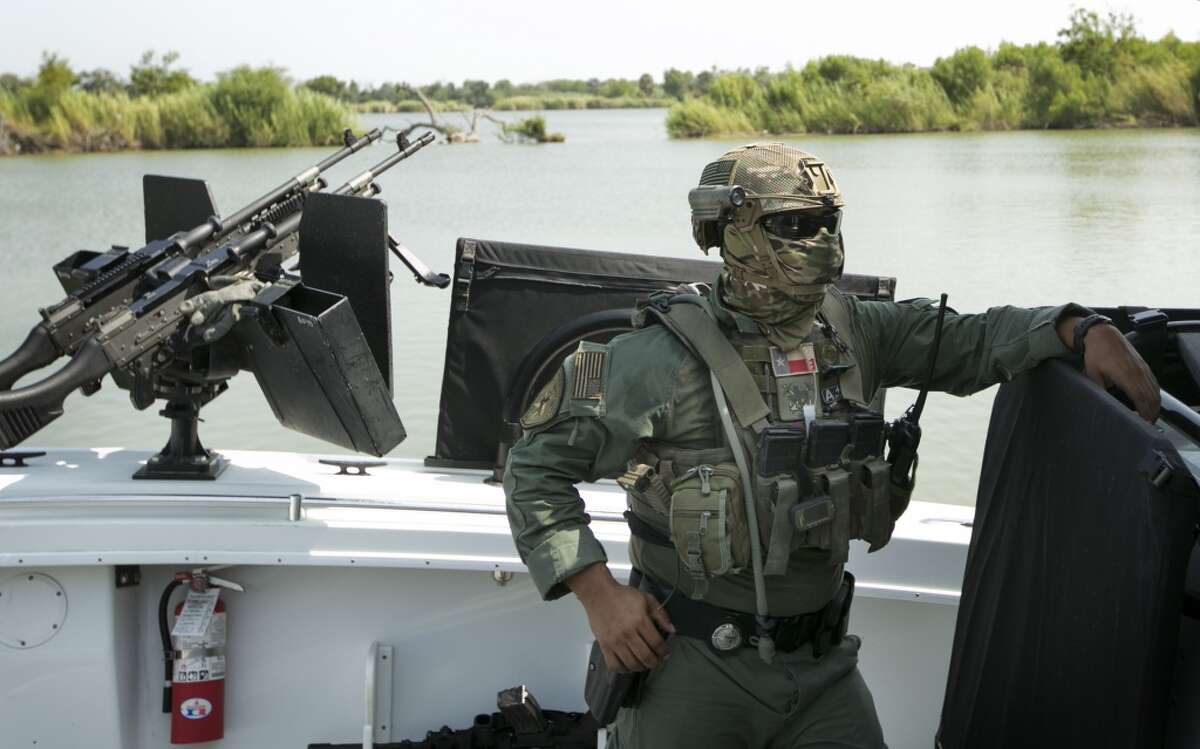 A masked Texas Department of Public Safety trooper prepares to patrol the Rio Grande River between McAllen, Texas, and Reynosa, Tamaulipas, Mexico, on a boat armed with M240 machine guns. The boat patrols are part of the law enforcement surge to attempt to secure the border. (AP Photo/Austin American-Statesman, Jay Janner)