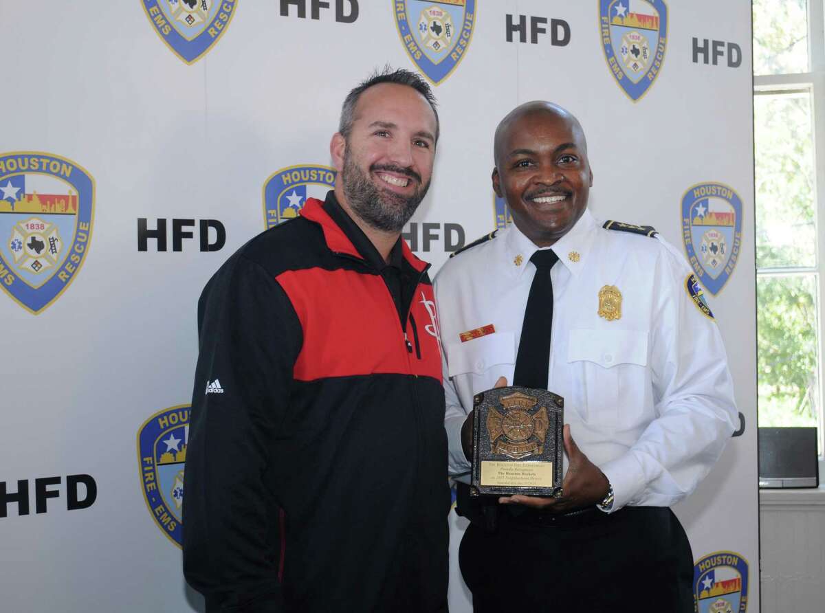 Houston Interim Fire Cheif Rodney West,right, presenting the 2015 Neighborhood Heroes Award to Mike Schnieders(77096) of the Houston Rockets.
