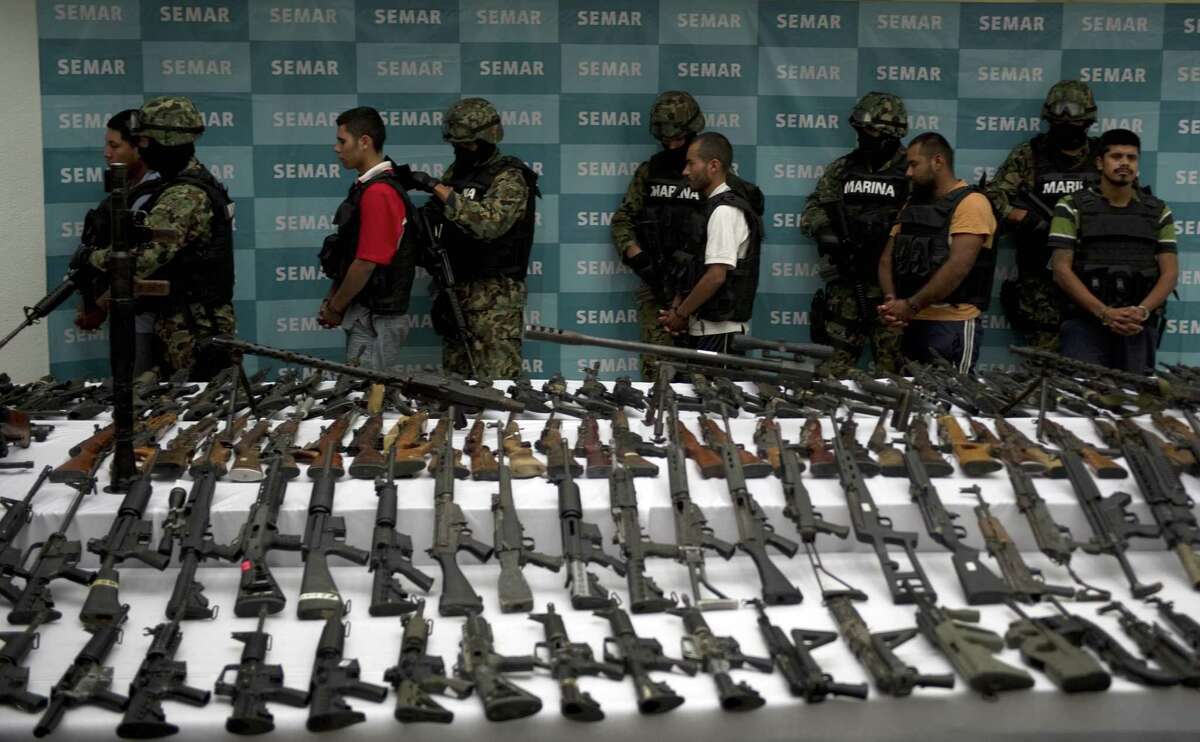 Mexican marines escort five alleged drug traffickers of the Zetas drug cartel in front of hand grenades, firearms, cocaine and military uniforms seized to alleged members of the Zetas drug traffickers cartel and presented to press on June 9, 2011 at the Navy Secretaryship in Mexico City. Fiven men were arrested and more than two hundred rifles, eleven pistols, military uniforms, differents caliber ammunitions and more than 200 kg of cocaine were seized in the Coahuila and Nuevo Leon States by the Navy. AFP PHOTO/ Yuri CORTEZ