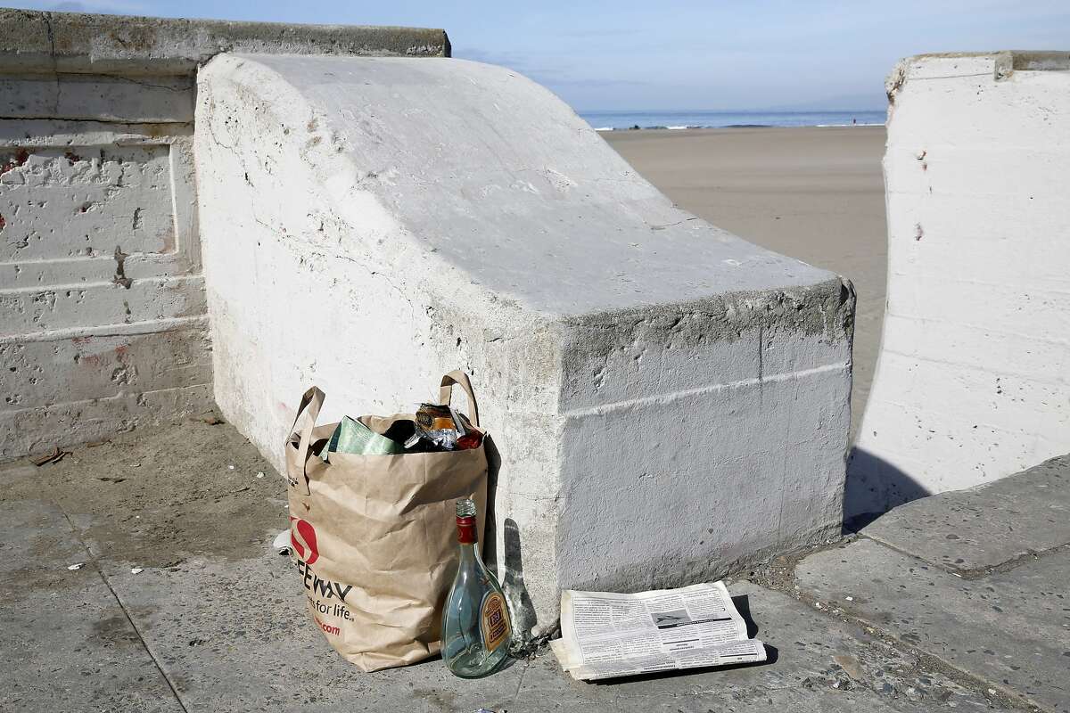 A bag of trash, a newspaper and an empty glass bottle on the ground near stairwell 13 at Ocean Beach in San Francisco, California, on Thursday, Nov. 5, 2015.