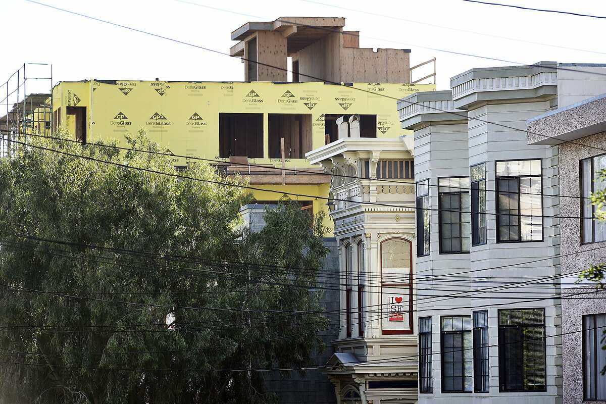 A pro-affordable housing poster hangs in a window as construction of new housing developments looms over older buildings on Hill St. at Valencia St. in the Mission District of San Francisco, CA Friday, November 6, 2015.