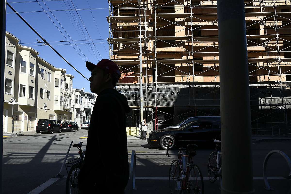 Pedestrians walk past new housing construction at 3420 18th St. in the Mission District of San Francisco, CA Friday, November 6, 2015.