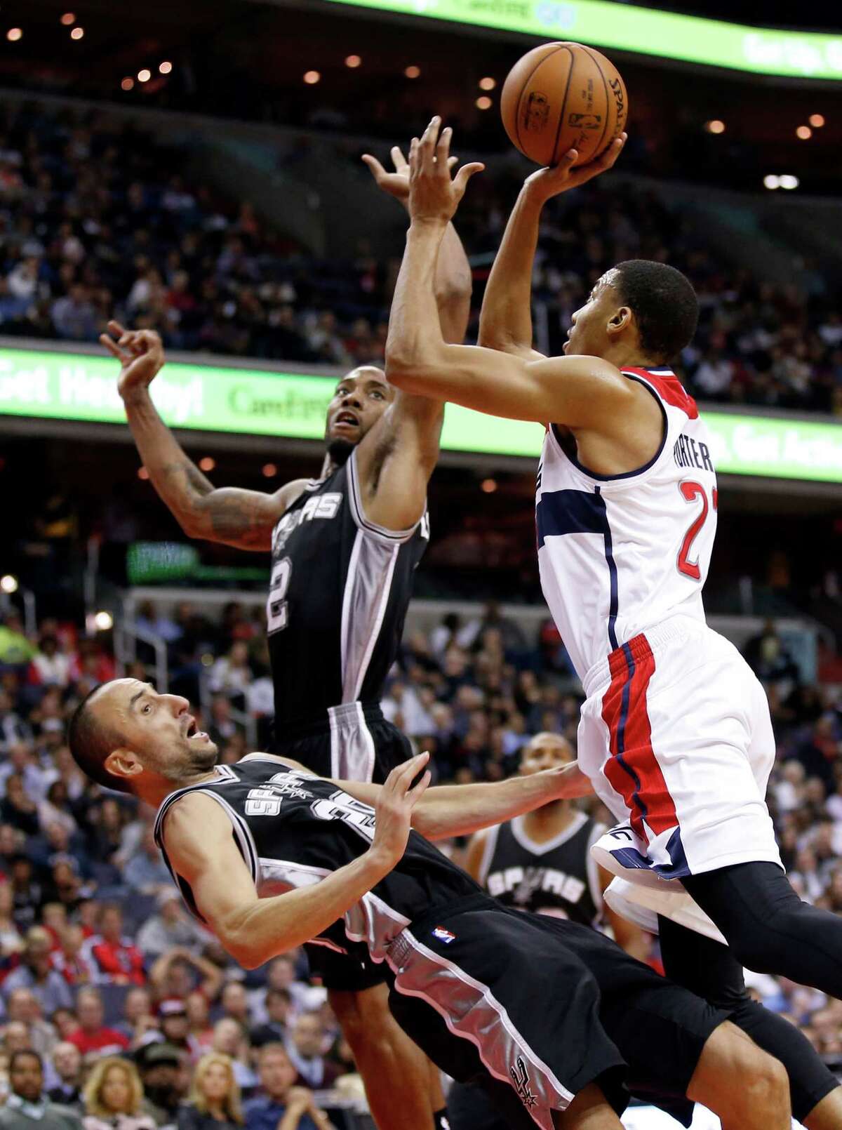 Spurs guard Manu Ginobili draws a charge from Washington Wizards forward Otto Porter Jr. with forward Kawhi Leonard nearby during the second half on Nov. 4, 2015, in Washington. The Wizards won 102-99.