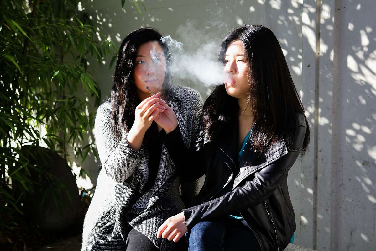 (l-r) Monica Lo and Tiffany Wu smoke a joint before work at Peace Plaza in Japantown in San Francisco, California on Friday, November 6, 2015. They are childhood friends and roommates that are working to lessen the stigma of cannabis in the Asian community.