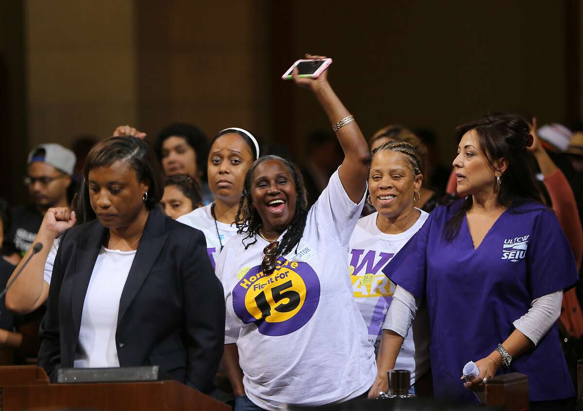 FILE - In this May 19, 2015, file photo, Laphonza Butler, President of SEIU ULTCW, the United Long Term Care Workers' Union, far left, joins workers demanding the Los Angeles City Council to vote to raise the minimum wage. The council gave initial approval to raising minimum pay in the nation's second-largest city to $15 an hour by 2020. SEIU's state council announced an initiative Tuesday, Nov. 3, 2015, that would raise the minimum wage to $15 an hour by 2020 and require at least six paid sick days a year, double the number now offered to low-wage workers. Meanwhile, SEIU's United Healthcare Workers West already has been gathering signatures for a separate measure that would raise the minimum wage by $1 an hour until it hits $15 an hour in 2021. (AP Photo/Damian Dovarganes, File)
