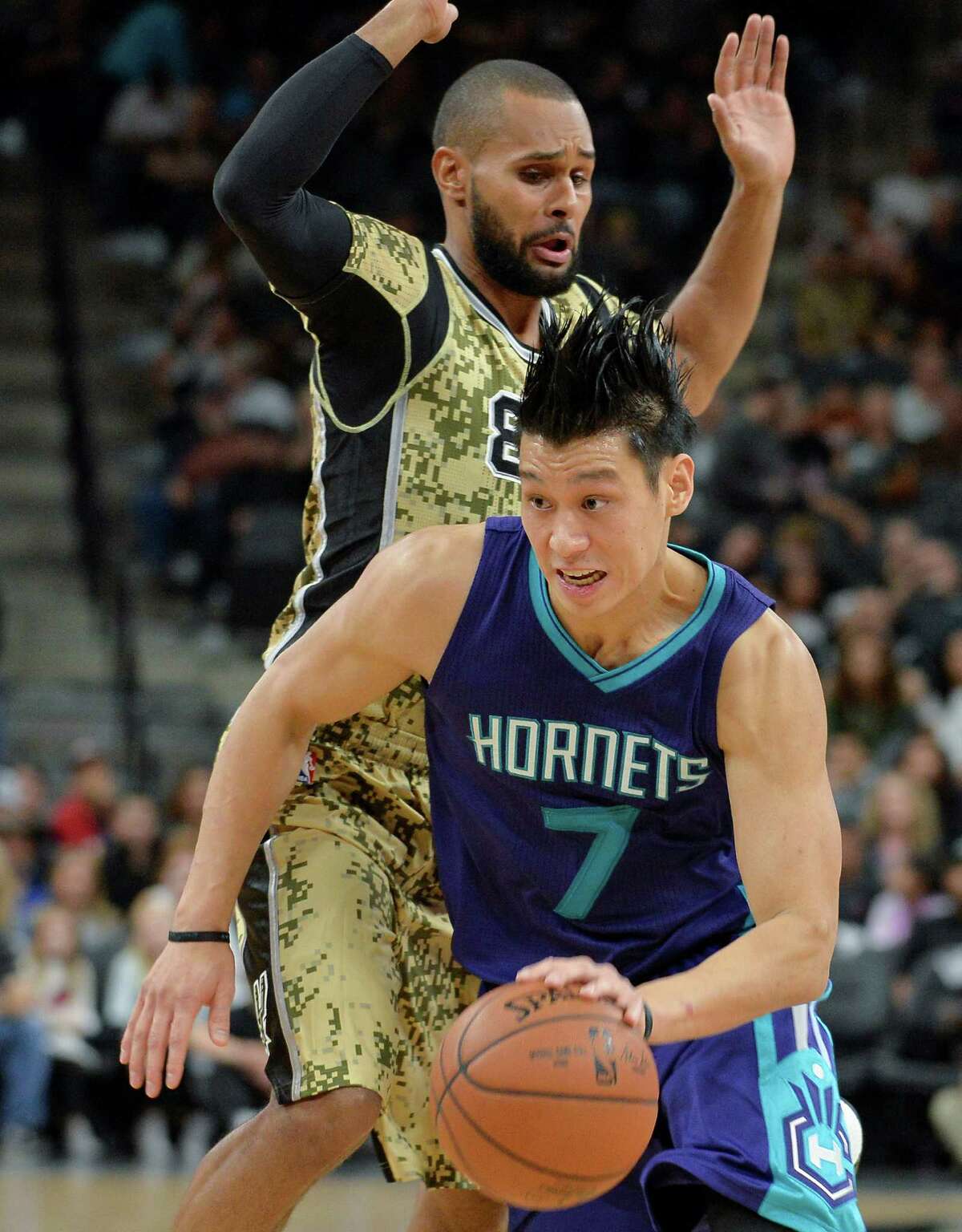 Charlotte Hornets guard Jeremy Lin (7) drives around San Antonio Spurs guard Patty Mills, of Australia, during the first half of an NBA basketball game, Saturday, Nov. 7, 2015, in San Antonio. (AP Photo/Darren Abate)