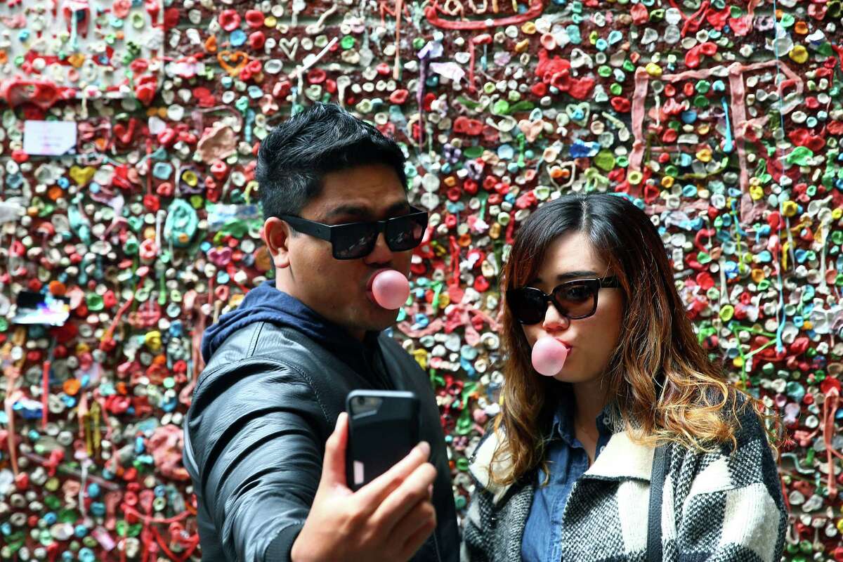 Rex and Ann Narvaez, of San Diego snap a selfie in Post Alley the day before the gum wall will be completely cleaned for the first time in 20 years, Monday, Nov. 9, 2015. People stopped in throughout the day, to take photos and add to the wall before it's three-day long cleaning.