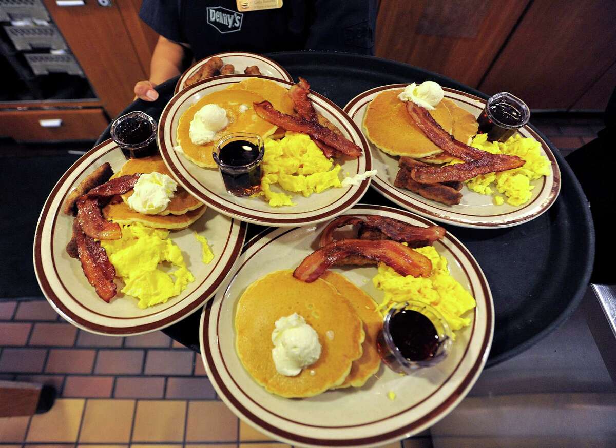 Server Leslie Ramirez carries a tray full of Grand Slam breakfasts to customers at a Denny's restaurant.