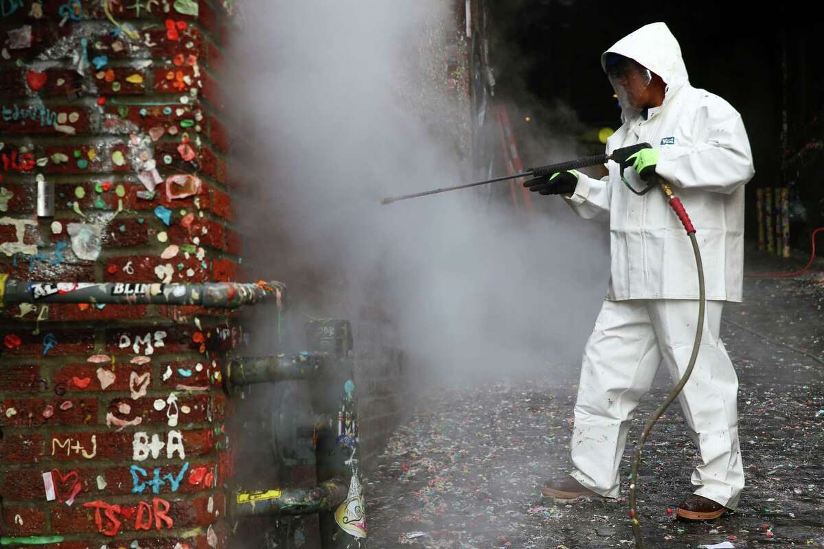 Javier Ramirez began cleaning 20 years worth of gum from the walls of Post Alley at Pike Place Market, Tuesday, Nov. 10, 2015.