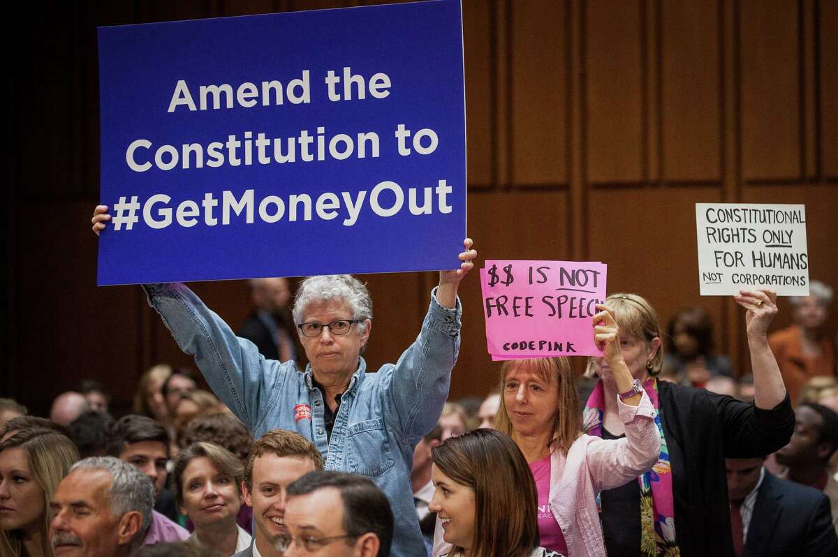 Code Pink activists hold up signs in support of a proposed constitutional amendment on campaign finance during a Senate Judiciary Committee hearing in Washington, D.C., U.S., on June 3, 2014 (Pete Marovich/Bloomberg)