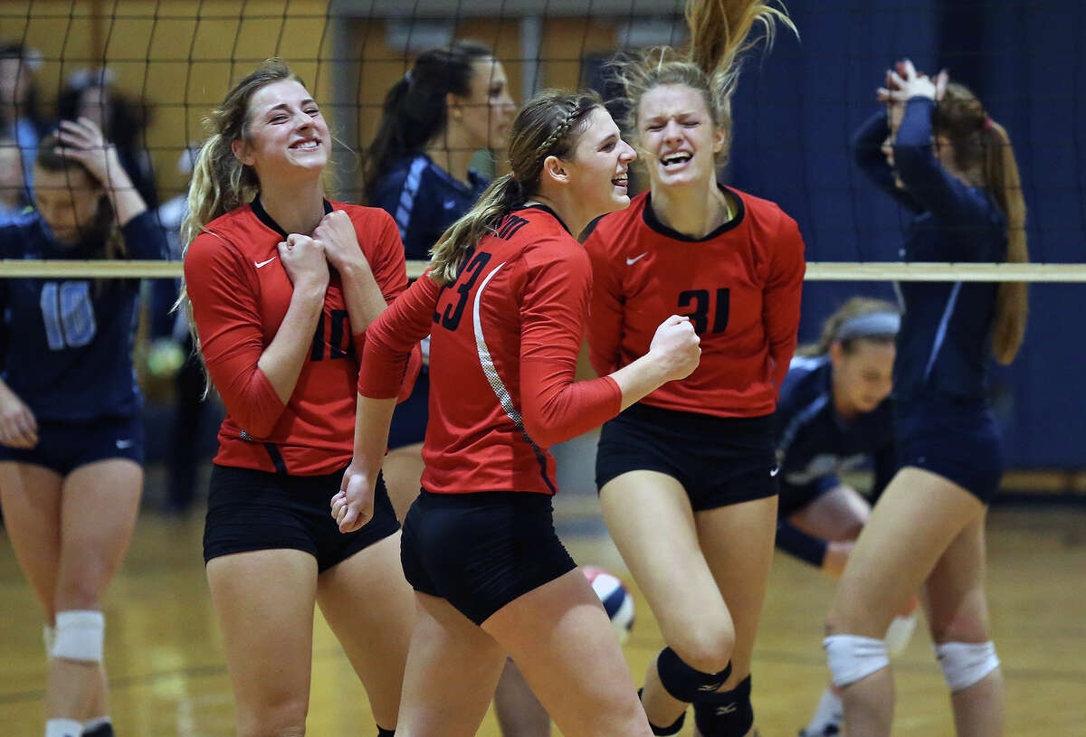 KK Payne (center) pumps her fist in victory with teammates Skylar Clark (10) and Brooke Kanas as New Braunfels Canyon beats Johnson 3-1 to advance to the 6A regional tournament on Nov. 10, 2015.