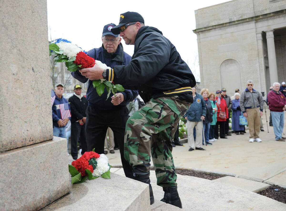 U.S. Marines veteran Donald Sargeant, left, and U.S. Army veteran James Clifford place a wreath during the American Legion Post 29 Veteran's Day Ceremony in front of Restoration Hardware in Greenwich, Conn. Tuesday, Nov. 11, 2015. Local veterans were remembered and honored in the ceremony with a flag-raising, placing of a wreath and speeches from town leaders.
