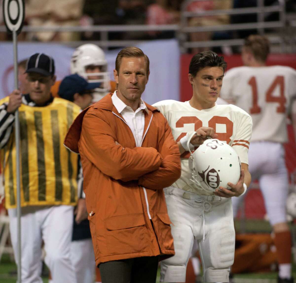 University of Texas coach Darrell Royal (Aaron Eckhart) and star safety Freddie Steinmark (Finn Wittrock, right) observe from the sidelines in "My All-American."