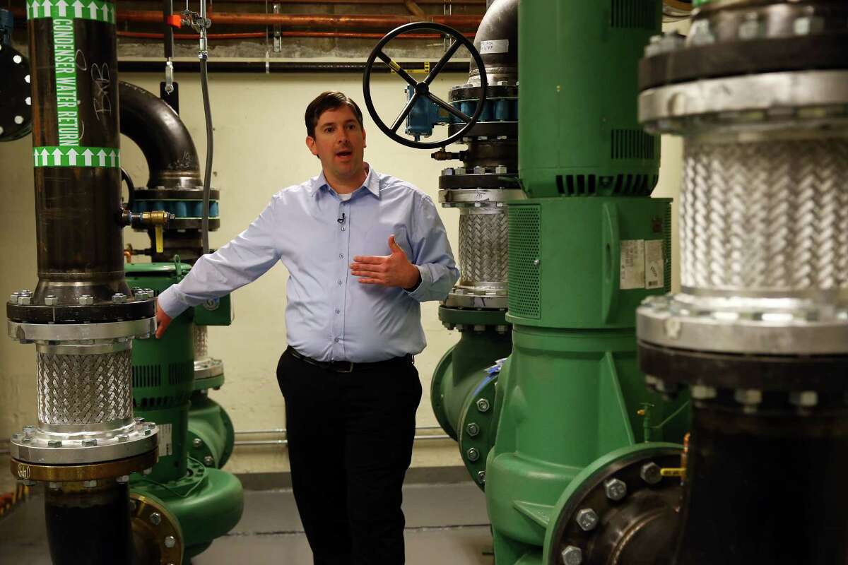McKinstry Project Manager Adam Myers explains the workings of a new "district energy" system in the Westin Building in Downtown Seattle, Thursday, Nov. 12, 2015. The system will recycle waste heat from the many Internet servers housed in the building and pipe it across the street to heat Amazon's newest buildings.